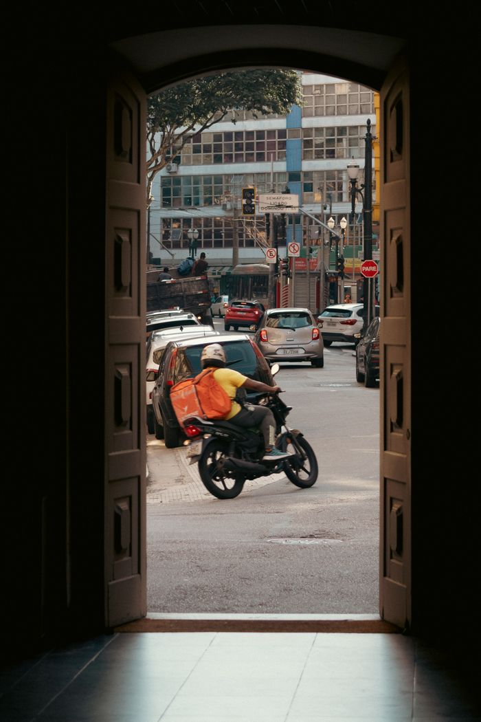 services-03 Motorcyclist in a busy city street captured through an open doorway.